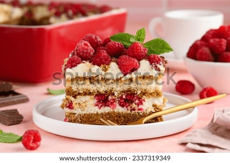 A piece of tiramisu with raspberries on a white plate on the table. Traditional Italian dessert. Selective focus