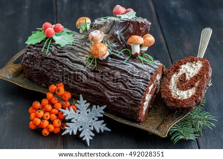 Piece of the traditional Christmas cake, snowflake and red berries on a wooden table.
