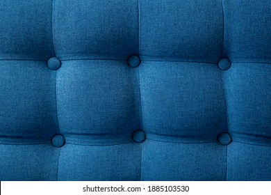 A piece of upholstered furniture with a classic Chesterfield pattern background with buttons. Modern blue furniture fabric. Elegant luxury sofa upholstery. Interior backdrop. Close-up photos