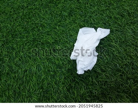 a piece of used tissue on a green synthetic grass