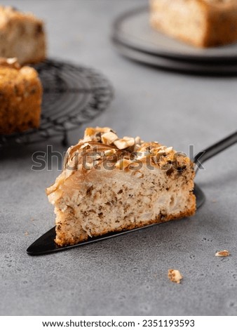 Piece of vegan chocolate pear cake with hazelnuts and almonds. Close up view of moist delicious fruit dessert. Festive bakery, homemade pastry. Grey background. Healthy snack or breakfast.