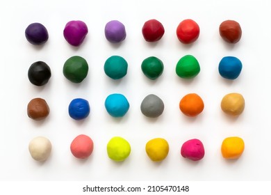 Pieces or balls of Colorful plasticine clay for modeling isolated on white background. Top view with shadow. Creativity children toys concept. 24 colors set.