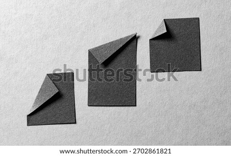 Pieces of black paper notes or sheets with folded edge dog-ear earmark and copy space for text on gray background, top view flat lay