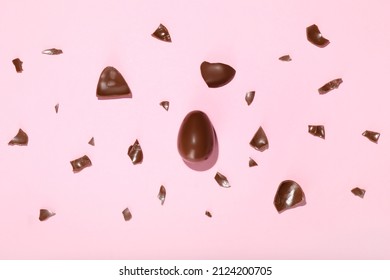 Pieces of broken chocolate Easter eggs on pink background