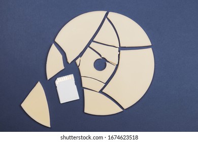 Pieces Of Broken Disc And Memory Card On Color Background