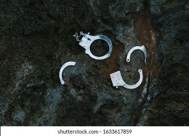 Pieces Of Broken Metal Handcuffs On Black Rock