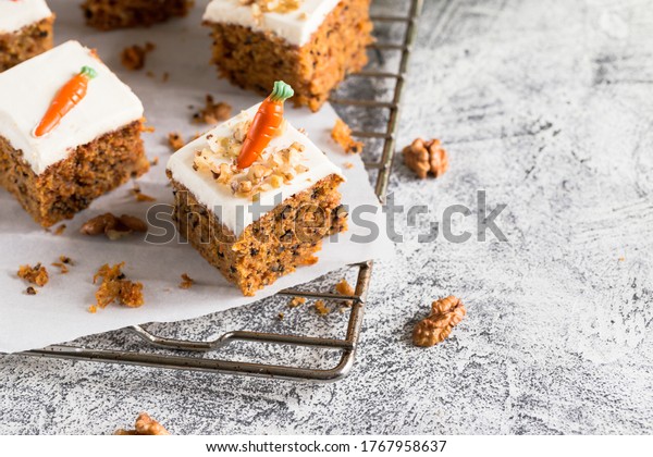 pieces of carrot cake with\
walnuts with icing cream on a light background. tinting. selective\
focus/