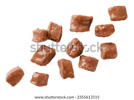 Pieces of cat food fly close-up on a white background. Isolated