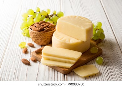 Pieces of cheese on wooden board with almonds and green grape on white wooden background. Selective focus. - Powered by Shutterstock