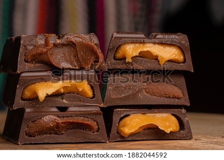 Pieces of chocolate bar filled with chocolate and vanilla cream on wooden plate