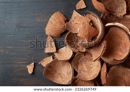 pieces of coconut fruit shell on black wooden surface, commercially important strong and durable fibrous material, used as fuel source, ingredient in various products, taken from above with copy space
