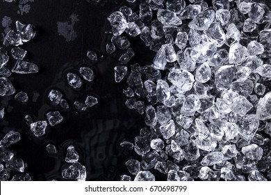 Pieces of crushed ice cubes on black background. Copy space, top view