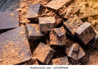 Pieces of dark bitter chocolate with cocoa powder on dark wooden background. The concept of confectionery ingredients - Shutterstock ID 1251899644