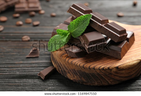 Pieces of\
dark chocolate with mint on wooden\
table