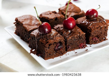 Pieces of fresh brownie with cherries and chocolate topping on table close-up. Delicious chocolate pie.