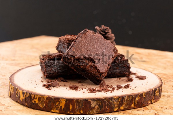 Pieces of fresh chocolate brownie on wooden plate\
on white background. Stack of fudgy chocolate brownies on white\
background, homemade bakery and dessert. Brownie chewy squares\
stack on wooden plate.