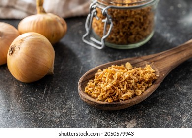 Pieces of fried onions in wooden spoon.