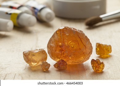 Pieces of Gum arabic with paint and paintbrushes in the background