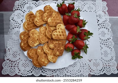 Pieces of heart-shaped waffles and strawberries on a white plate and colourful table. - Powered by Shutterstock