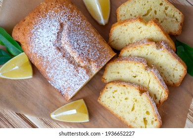 Pieces of lemon cake with full pie and lemons on rustic wooden board. Easy recipe of citrus dessert for everyday cooking. Homemade bakery by classic recipe.