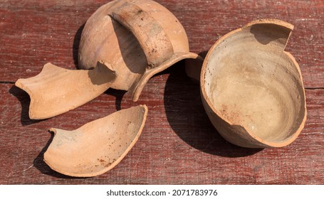 Pieces Of Old Clay Pot Or Traditional Jar On Wooden Table. Broken Antique Clay Pot In The History Museum 