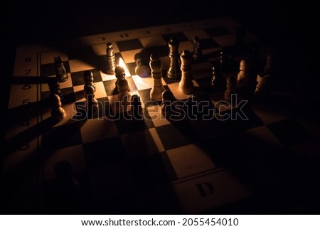 ?hess pieces on the chessboard against the background of a burning fire. Selective focus