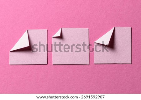 Pieces of paper notes or sheets with folded edge dog-ear earmark and copy space for text on pink background, top view flat lay
