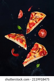 Pieces Of Pizza Flying With Herbs, Sauce And Spices On A Dark Background With Smoke