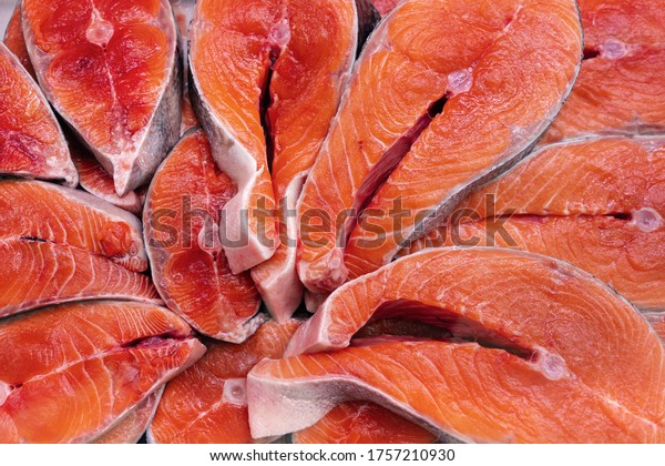 Lot of pieces raw Pacific Red Fish Chinook\
Salmon cut into steak and ready for cooking various delicious\
dishes. Close-up flat lay view of fresh wild fish King Salmon -\
delicacy Asian cuisine.
