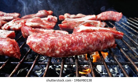 pieces of raw sausage and pork ribs cooking on a barbecue grill