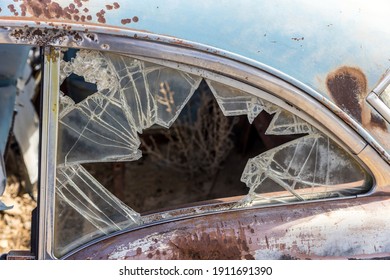 Pieces Of Safety Glass Create A Shattered Frame Showing Tumbleweed Inside Of A Rusty Old Car