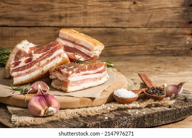 Pieces Of Salty High-fat Meat Cooked With Spices. Salo, Bacon, Lard, Silverside, Gammon. Garlic, Fresh Rosemary, Spices. Hard Light, Dark Shadow, Wooden Background, Copy Space