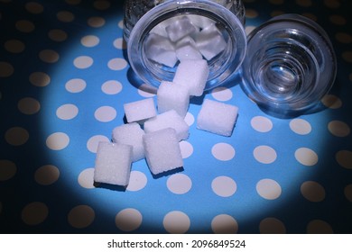 Pieces Of Suger Falling On A Blue Ground Dotted With White 