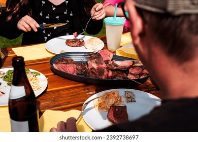pieces of tomahawk steak on serving plate placed on a wooden table, ready to be eaten