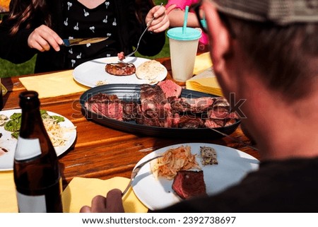 pieces of tomahawk steak on serving plate placed on a wooden table, ready to be eaten