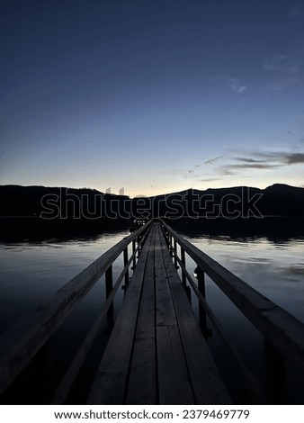 Pier after sunset with play of lights and shadows. Calm water and clear sky