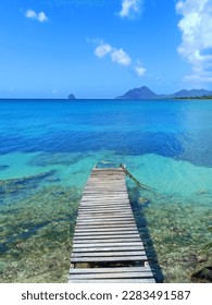Pier at beach in Landscape of the French West Indies. The wooden bridge stretches into the sea. Beautiful tropical with Mountain clouds and sky.