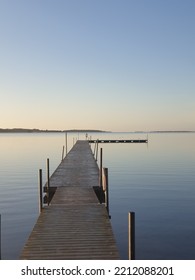 Pier Out Into Blue Still Water, Morning And Blue Sky