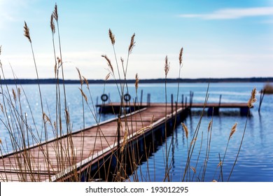Pier for pleasure and fishing boats on shore of Lake Ladoga in Karelia. Soft focus. In the foreground the tall grass