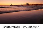 Pier silhouette Oceanside California USA. Pacific ocean tide tropical beach. Summertime gloaming atmosphere. Purple aesthetic gradient, calm twilight sky, pink violet dusk. Lights reflection in water.