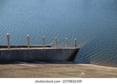 A pier is visible in the water, with a few wooden posts sticking out of the water. The water is calm and clear, with no visible movement. The scene is peaceful and serene, with the pier