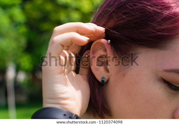 ほおに紫の髪とそばかすをかけた女の子に 穴を開けた耳 耳の軟骨が刺さる らせんピアシング 耳のカールや耳の上部に刺す穿刺 の写真素材 今すぐ編集