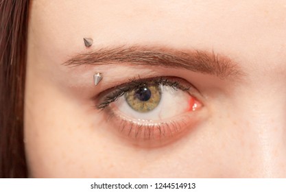 Piercing on the eyebrows of the girl. Cosmetic procedure for piercing the eyelid with a needle by a beautician. Eyebrow decoration