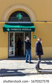 Pietrasanta, Lucca/Italy - Mar 11 2020 : Coronavirus In Italy, People Lined Up Waiting For Their Turn To Enter  The Pharmacy