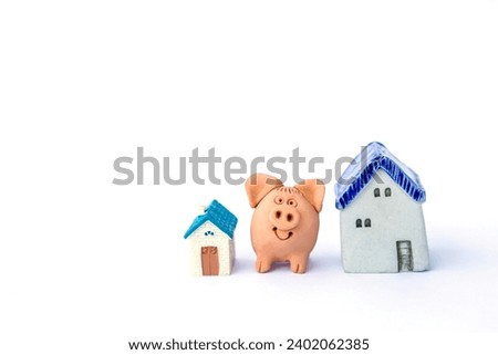 Pig clay sculpture with miniature house isolate on white background, property investment, house loand