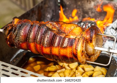 pig on a spit over a barbecue with potatoes