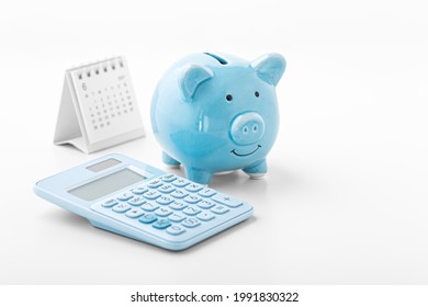 Piggy Bank With Blue Calculator And Calendar On White Background, Fiancial Goal, Money Saving Concept With Copy Space