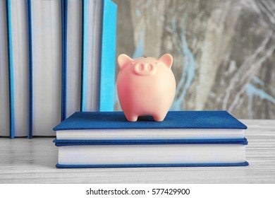 Piggy Bank With Books On Wooden Table