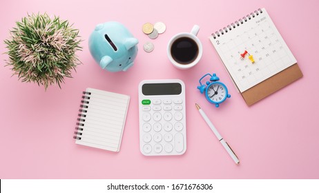 Piggy Bank, Calculator, Calendar, Clock And Coffee Cup On Pink Desk, Saving Money Concept, Flat Lay