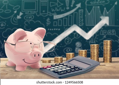 Piggy bank, calculator and coins on wooden